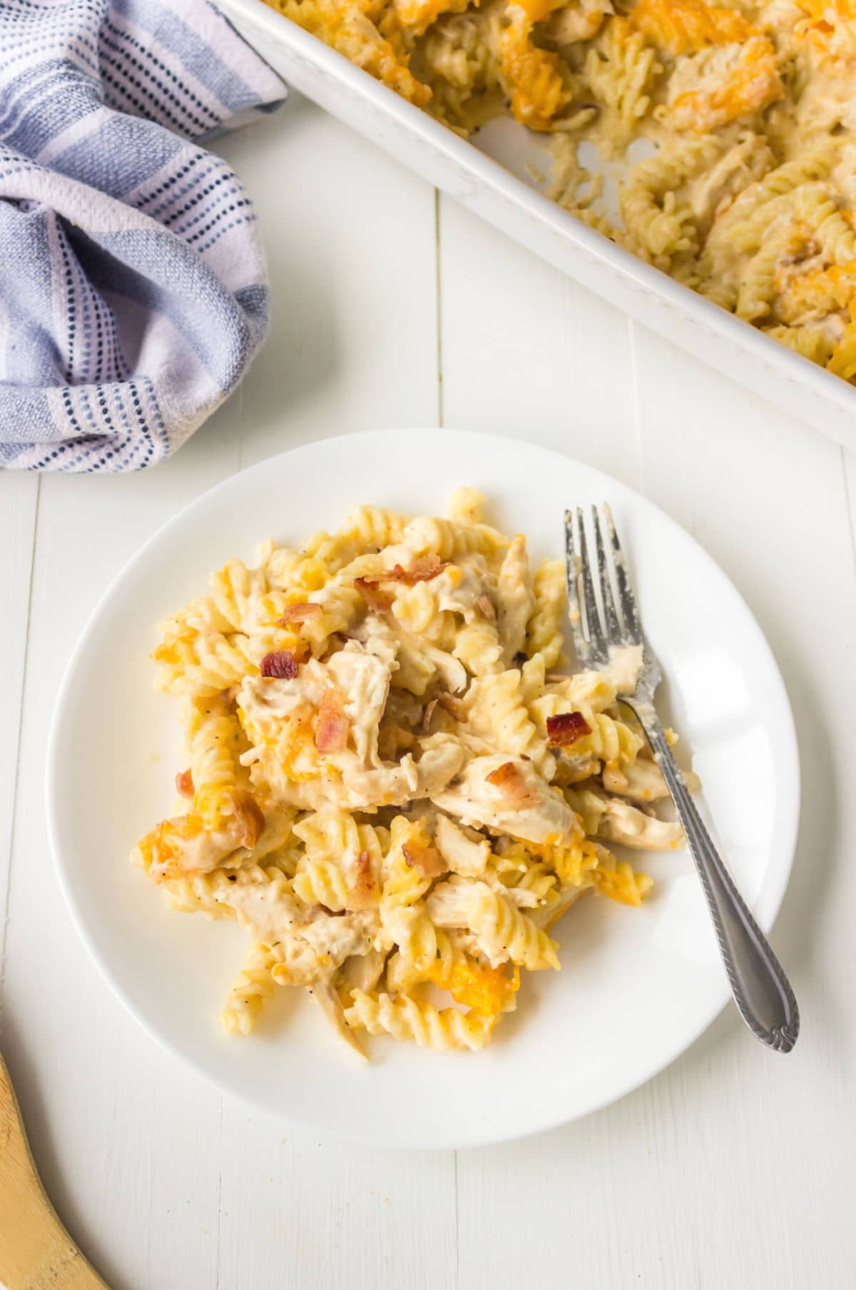 White plate with chicken bacon ranch pasta and a silver fork on it. 