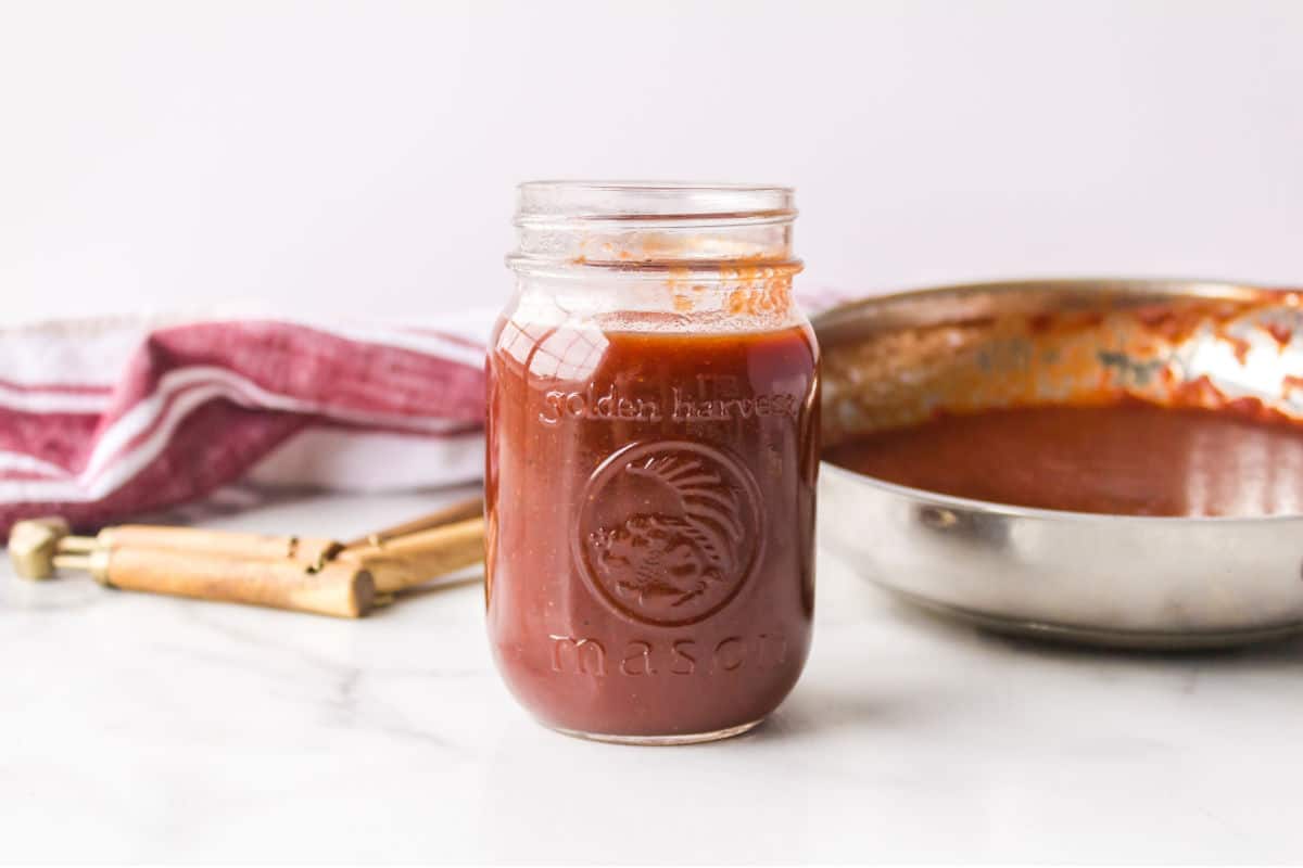 Jar of Dr Pepper barbecue sauce next to a pan and a dish cloth.