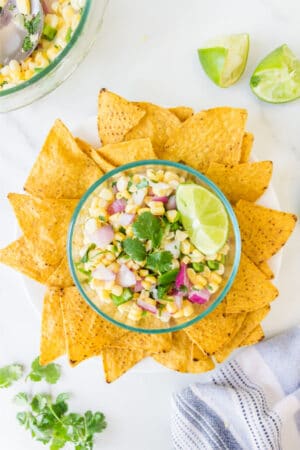 Dish of fresh corn salsa surrounded by tortilla chips.