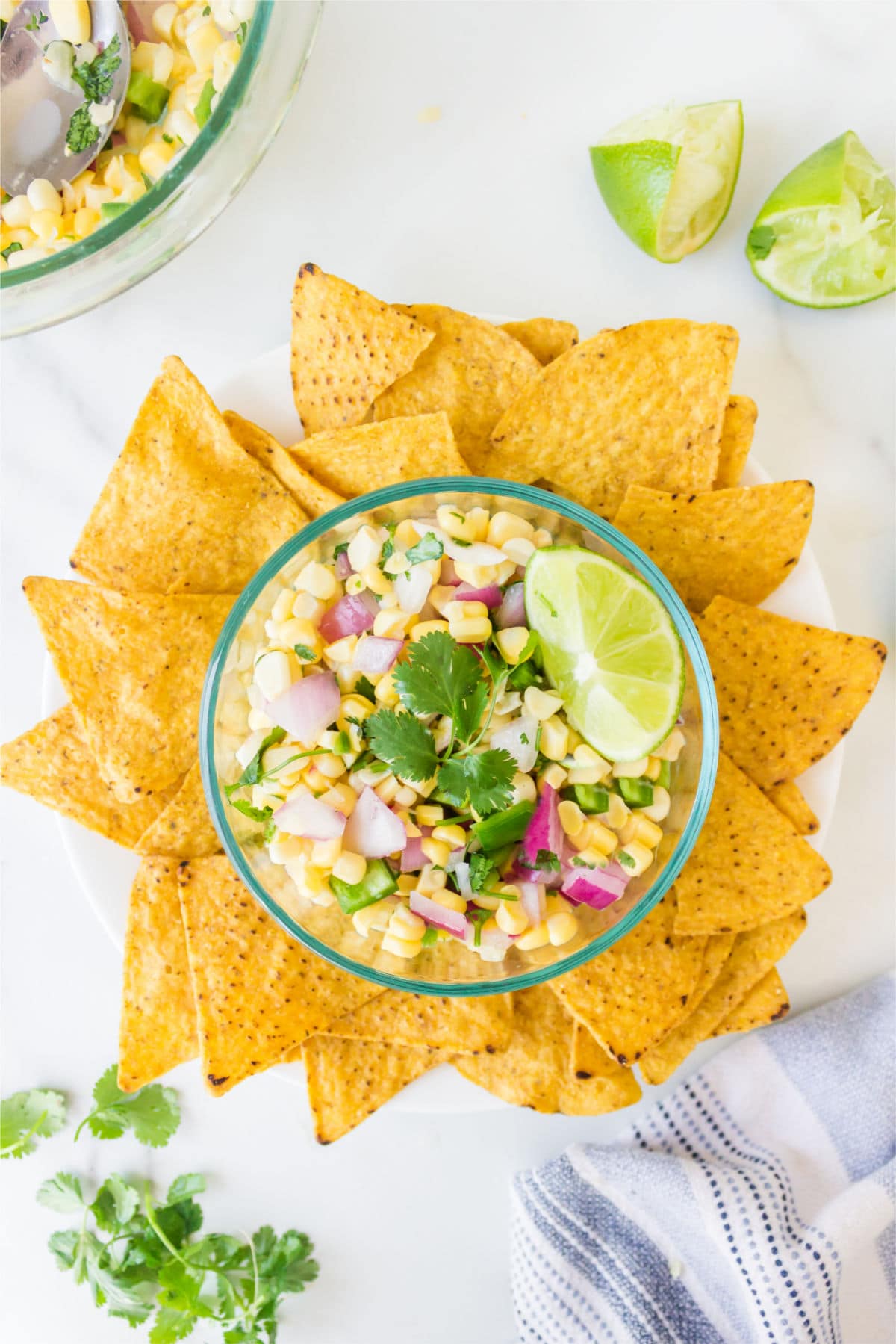 Dish of fresh corn salsa surrounded by tortilla chips. 