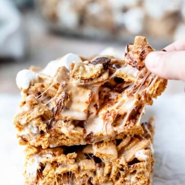 A hand pulling off a piece of a golden graham s'mores bar.