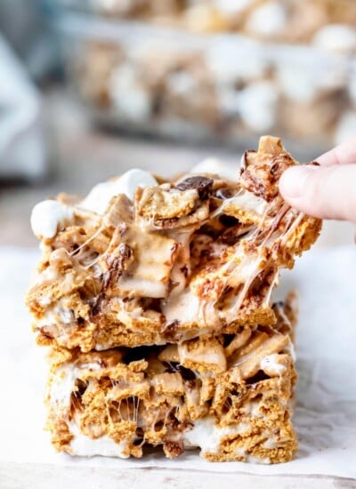 A hand pulling off a piece of a golden graham s'mores bar.