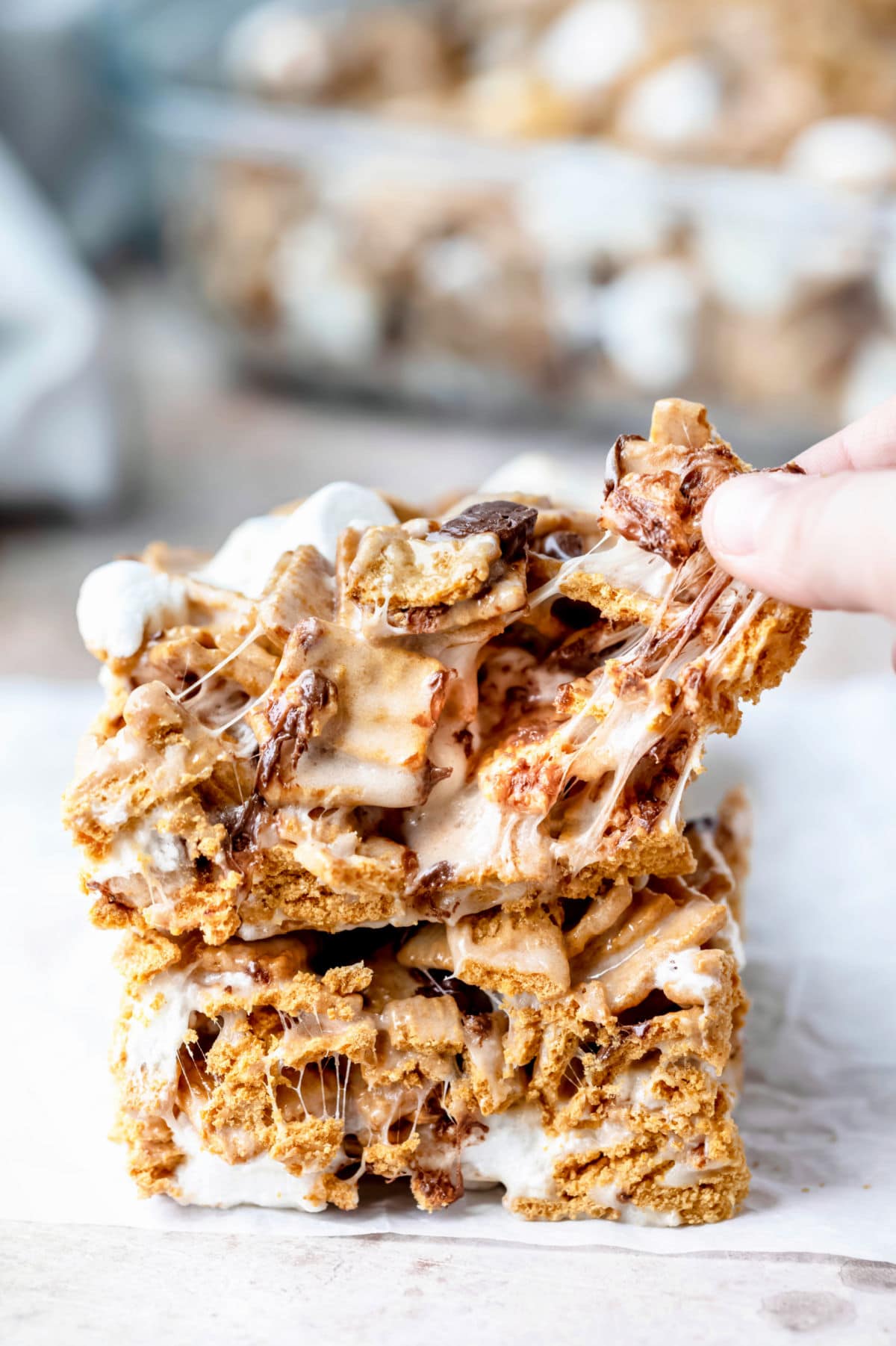 A hand pulling off a piece of a golden graham s'mores bar.