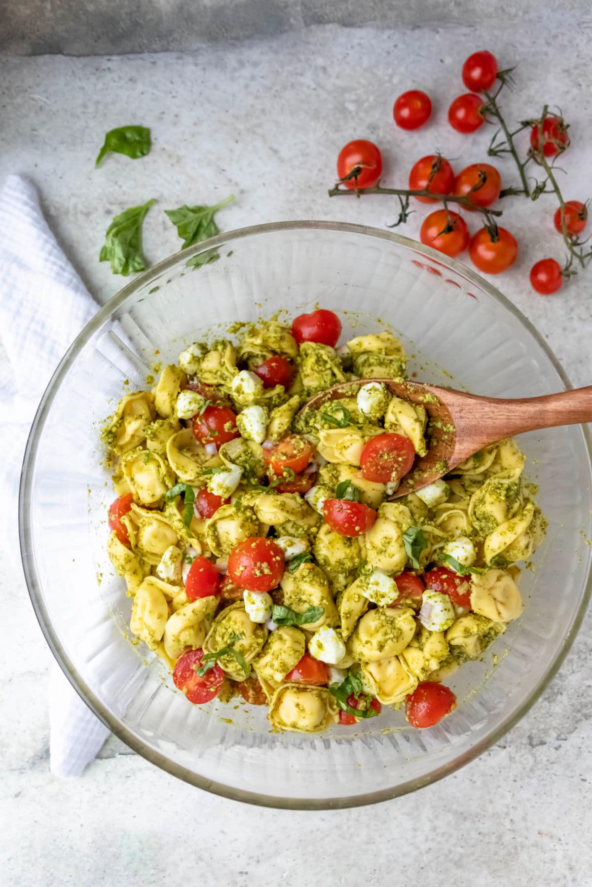 Pesto tortellini pasta salad in a glass mixing bowl. 