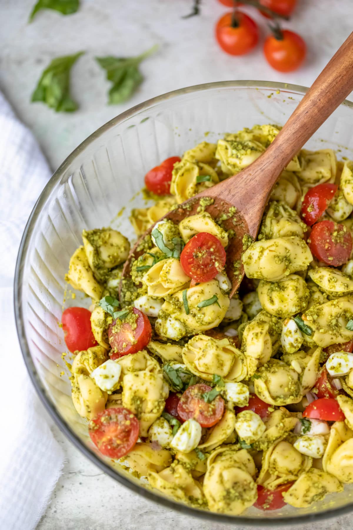 Cherry tomatoes on the stem next to a bowl of pasta salad. 