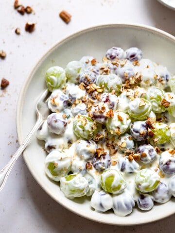 Grape salad in a shallow dish topped with chopped pecans.