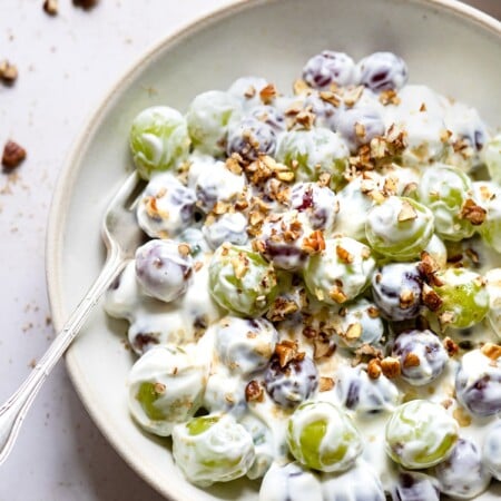 Grape salad in a shallow dish topped with chopped pecans.