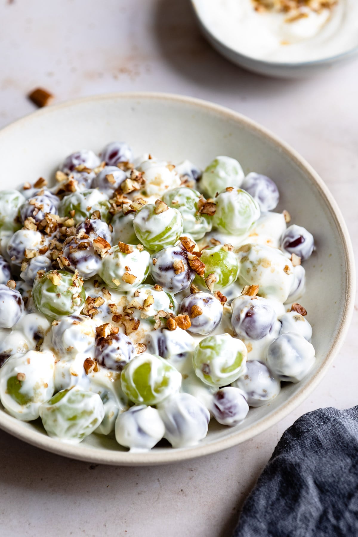 Bowl of grape salad next to a blue linen napkin. 