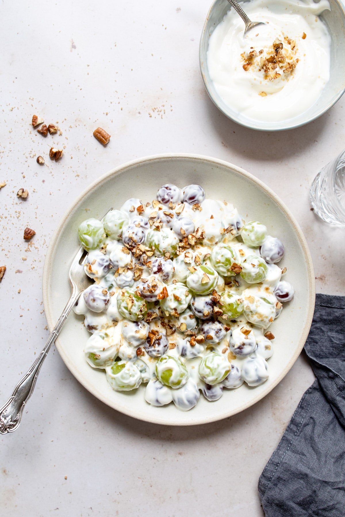 Plate of grape salad next to a dish of cream cheese topping.