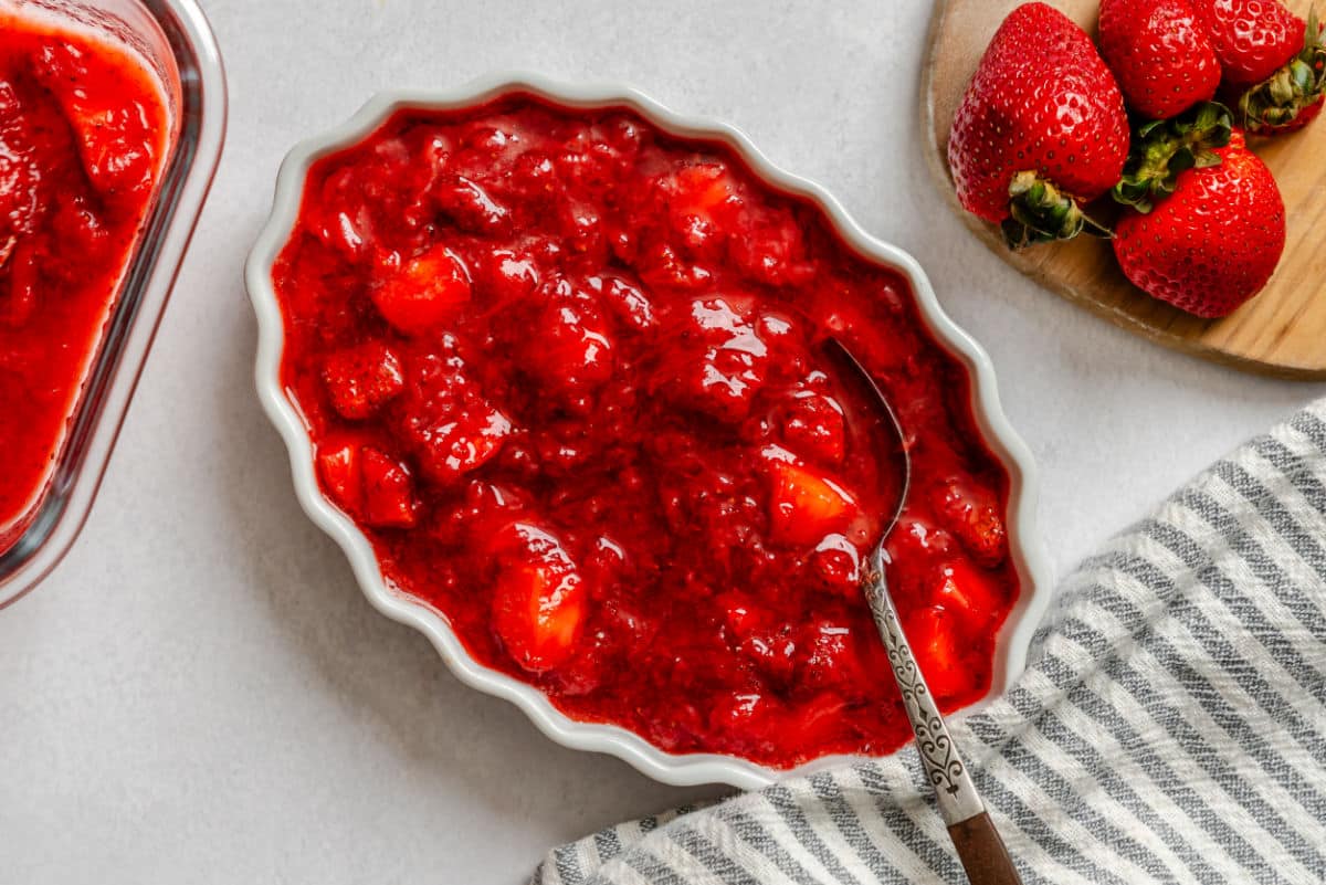 A dish of strawberry sauce with a silver spoon in it. 