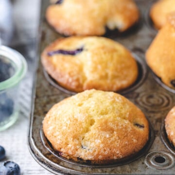Bakery style blueberry muffins in a vintage muffin tin.