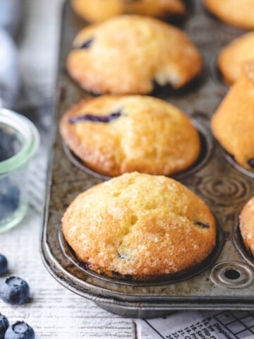 Bakery style blueberry muffins in a vintage muffin tin.