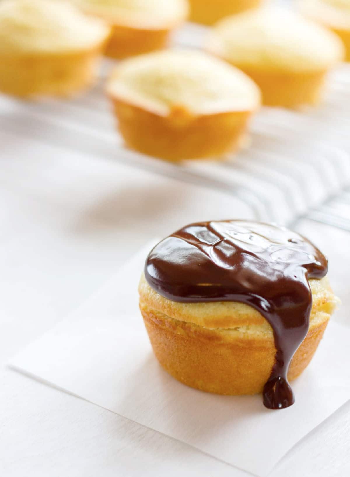 Boston cream pie cupcake on a piece of white parchment paper.