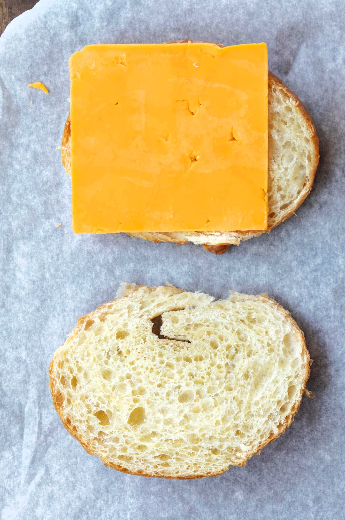 Slice of cheddar cheese on half of a croissant.