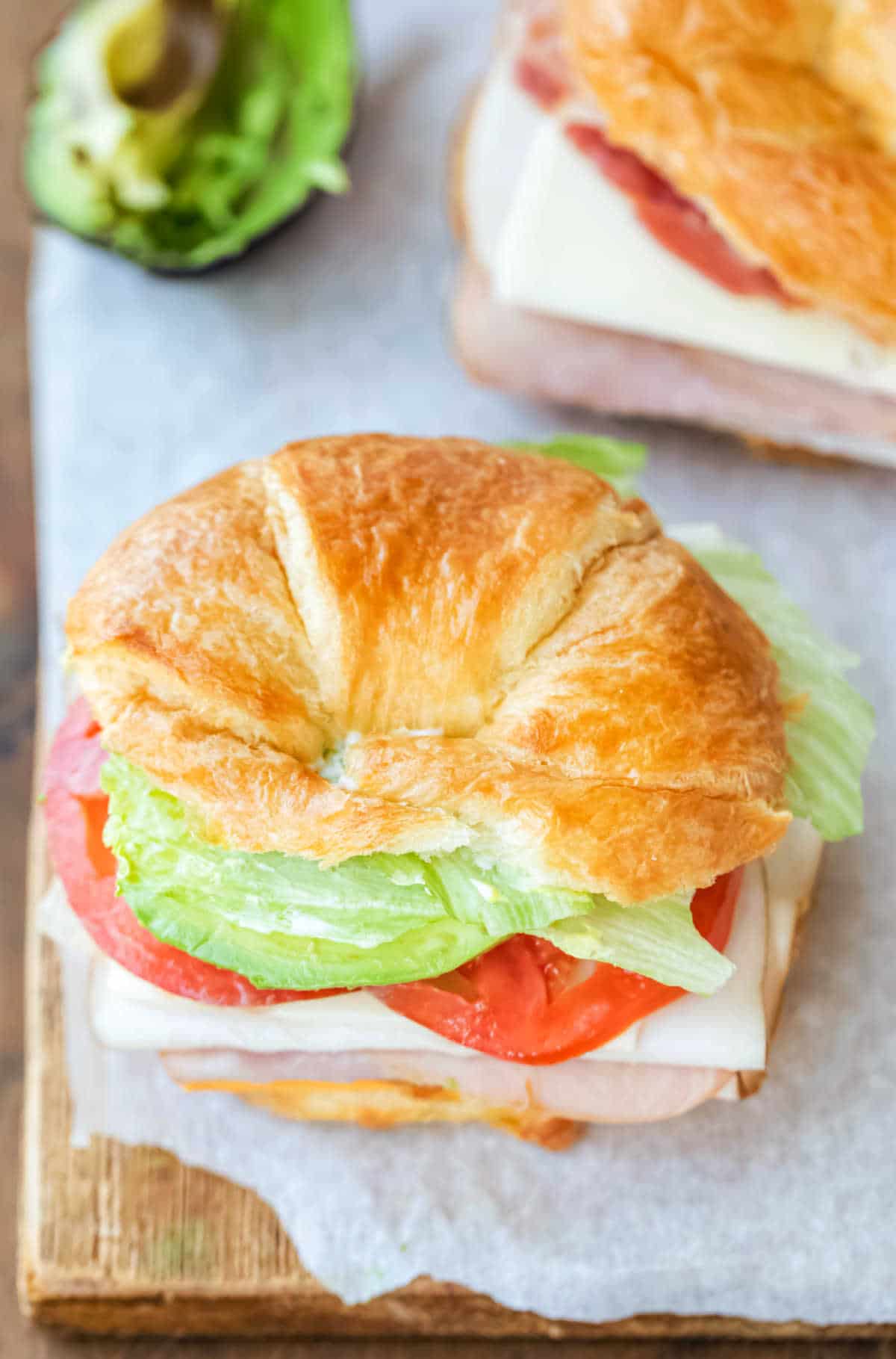 Overhead view of croissant sandwich on a piece of parchment paper. 