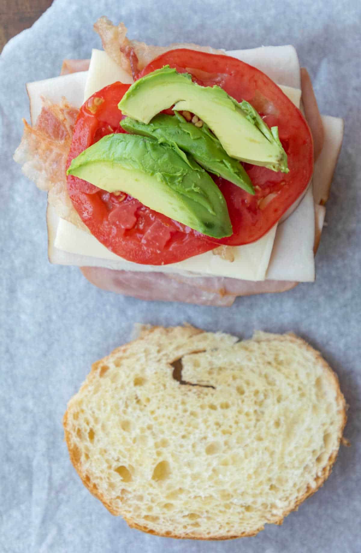 Slices of avocado and tomato on a croissant sandwich. 