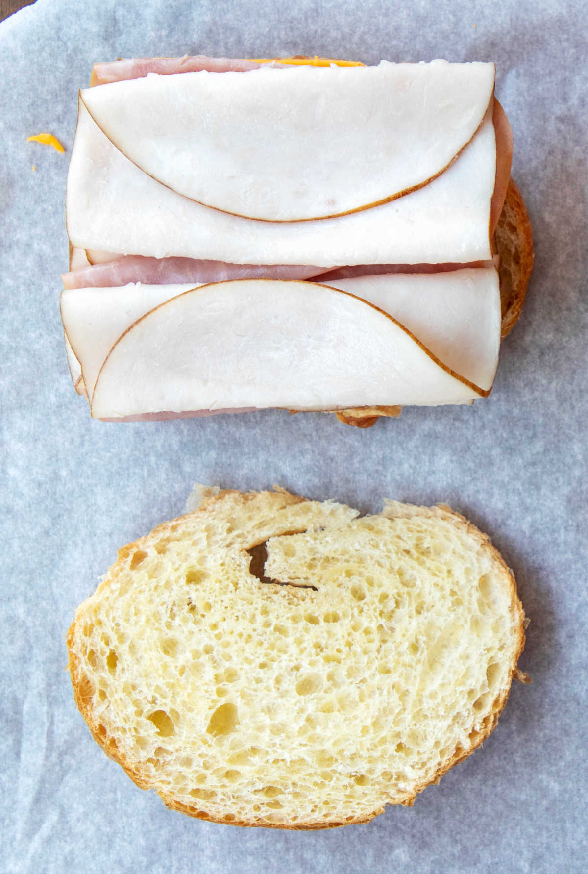Sliced ham, turkey, and chicken on half of a croissant.