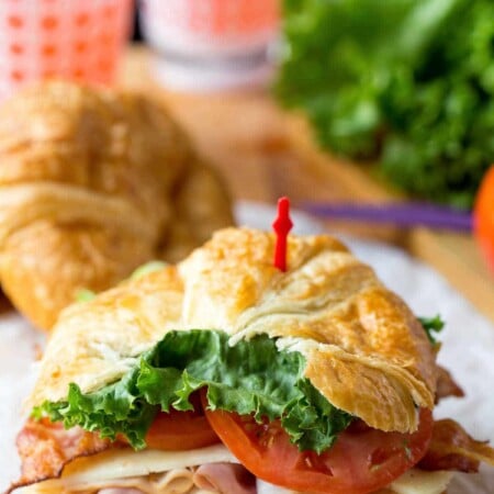 California club croissant sandwich on a piece of white parchment paper.