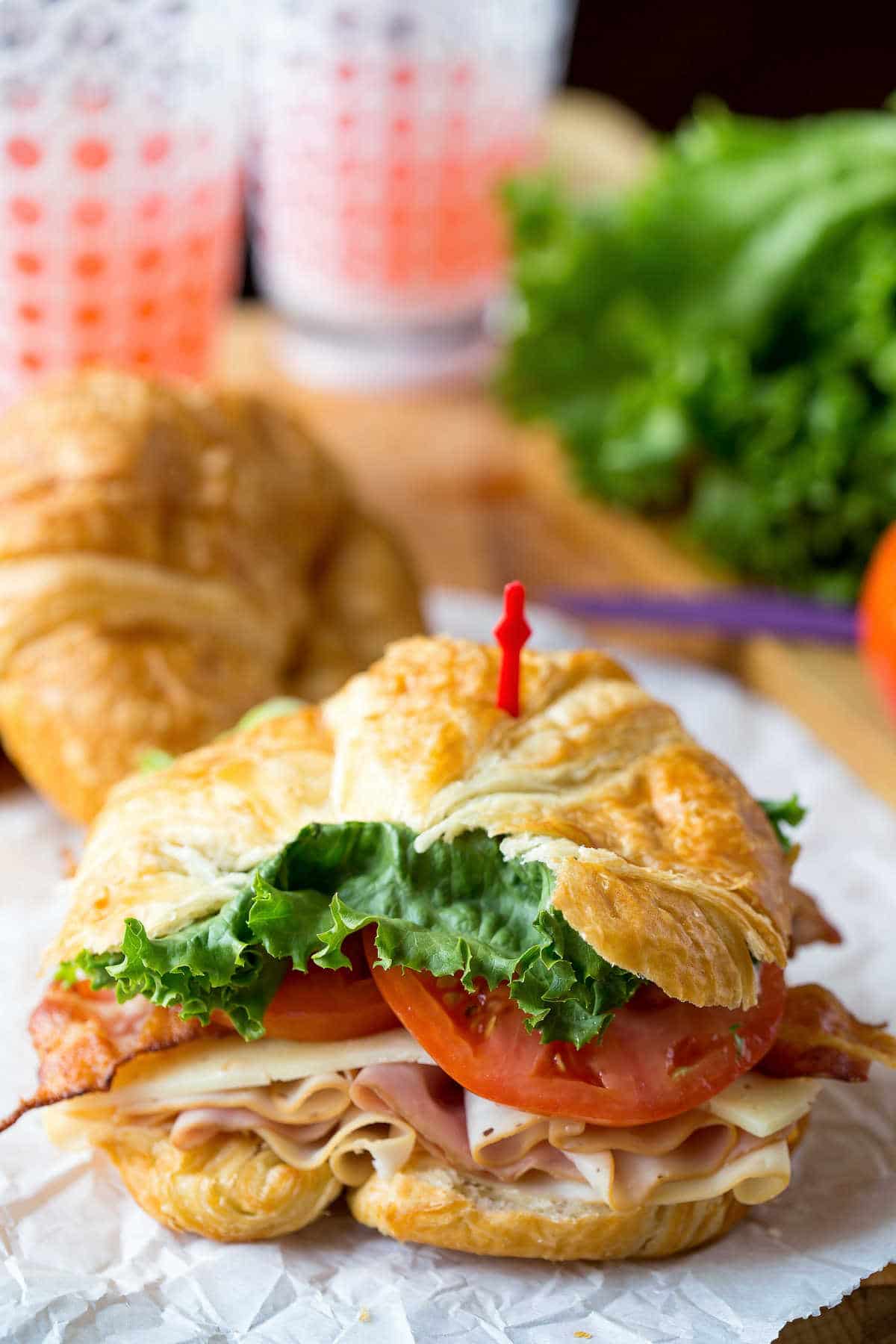 California club croissant sandwich on a piece of white parchment paper. 