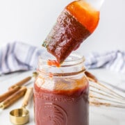 Basting brush dipping into a jar of barbecue sauce.