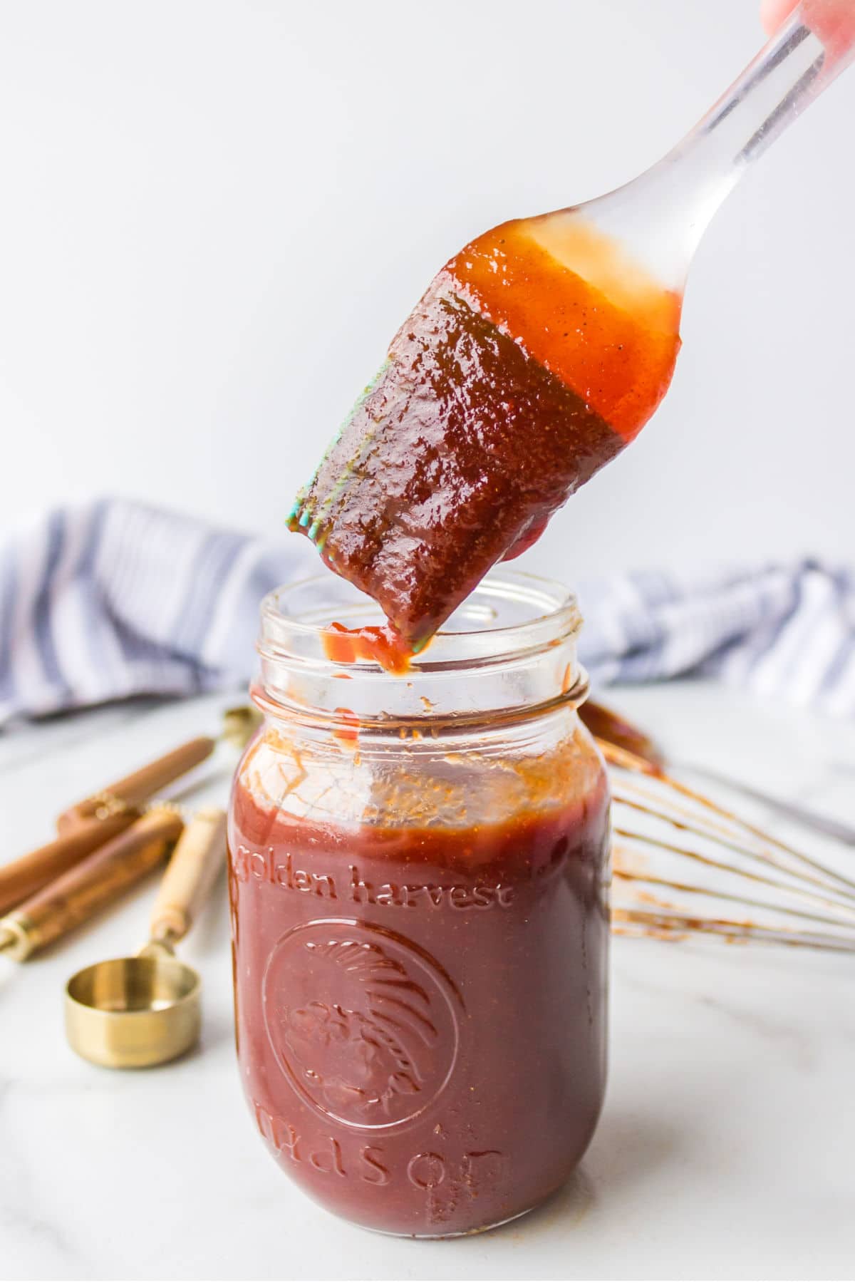 Basting brush dipping into a jar of barbecue sauce.