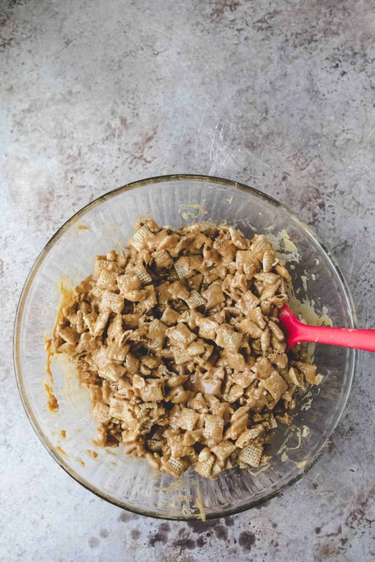 Chex coated with peanut butter sauce in a glass mixing bowl. 