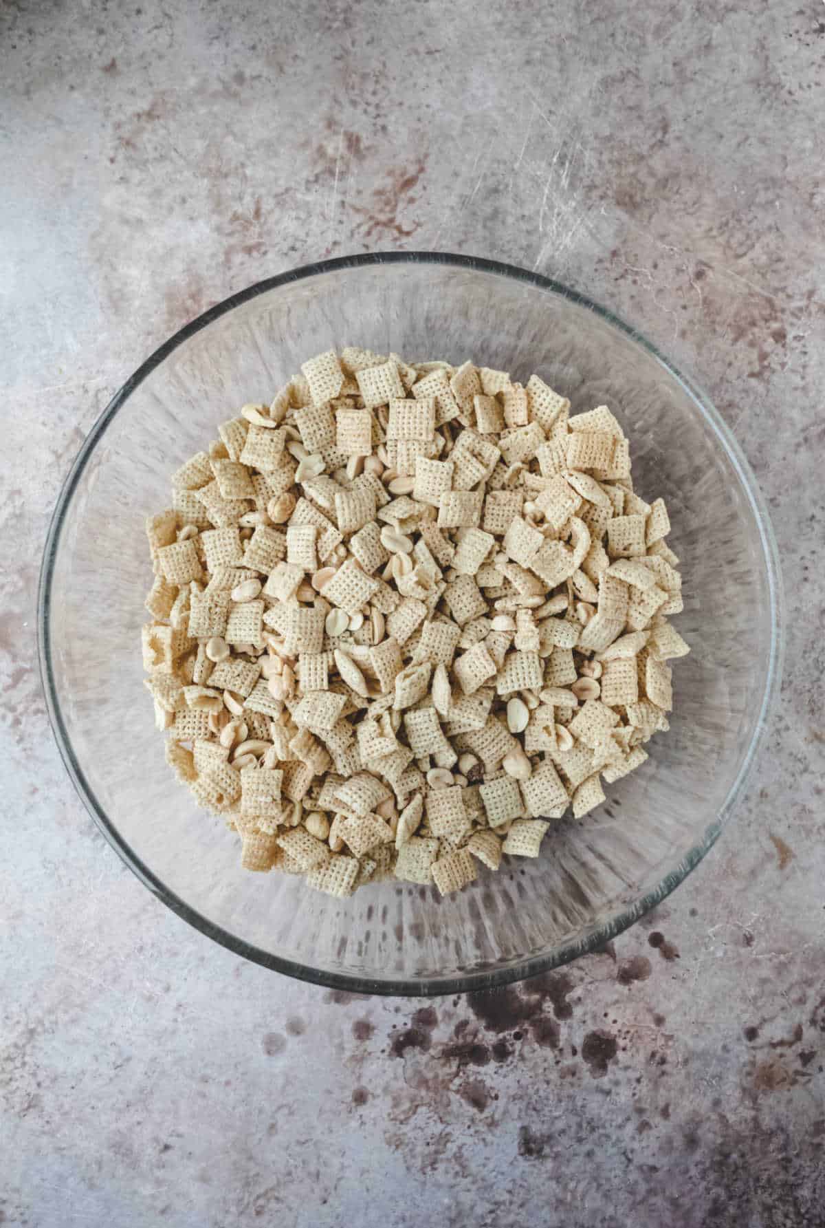 Chex cereal and peanuts in a glass mixing bowl.