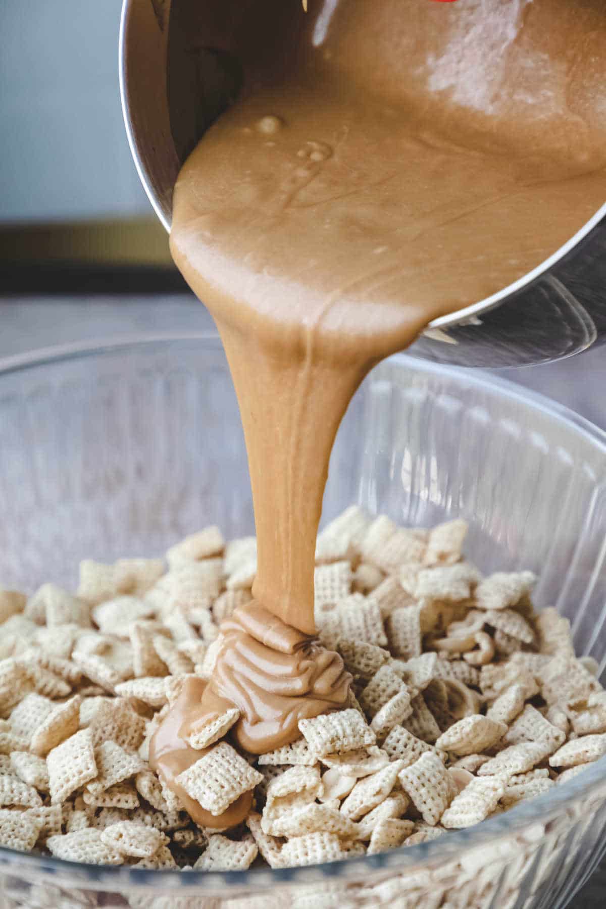 Peanut butter sauce pouring onto Chex cereal.