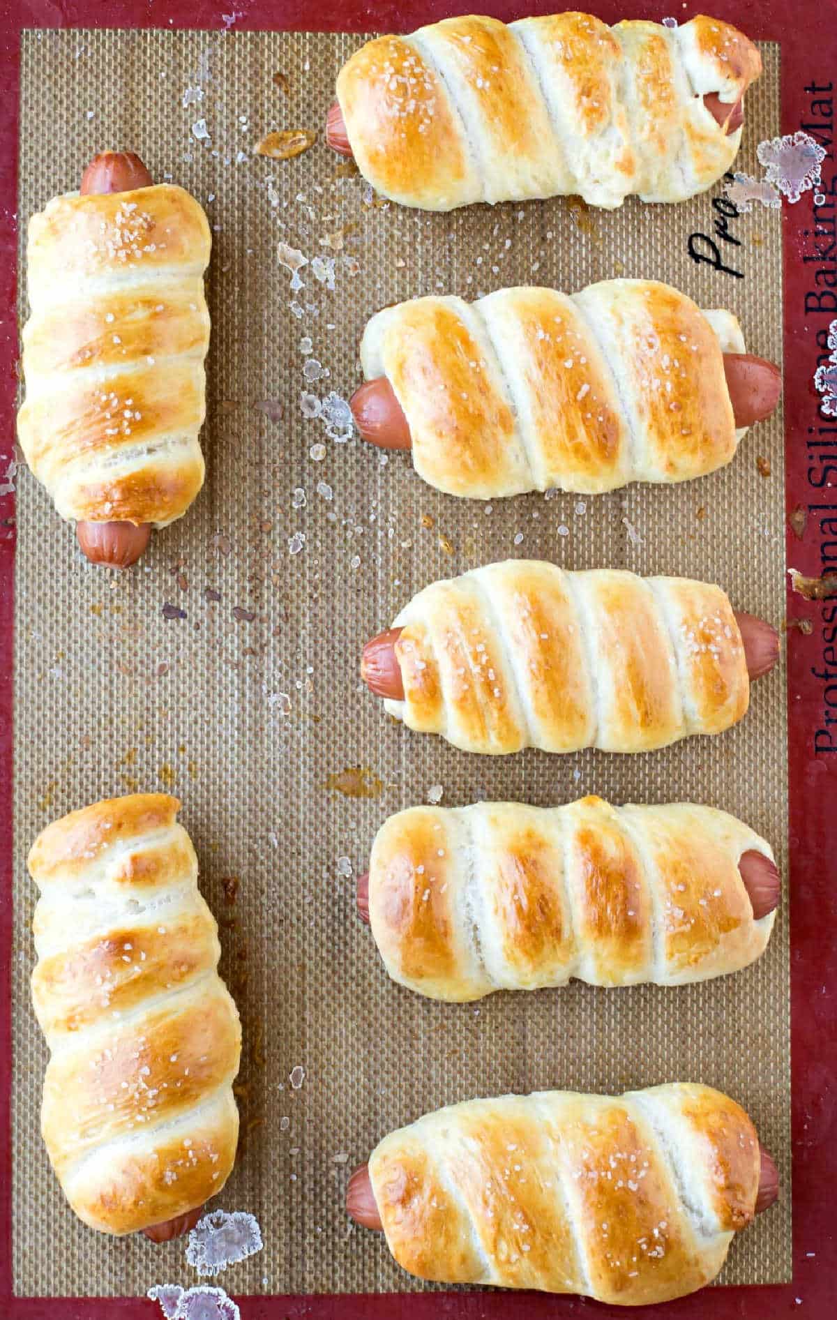 Baked pretzel dogs on a silicone baking mat. 