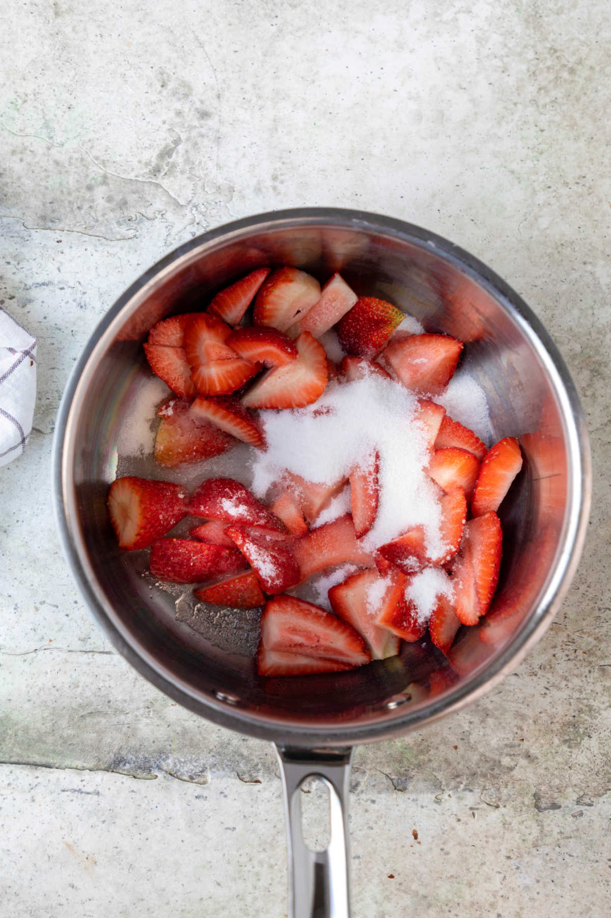 Strawberries and sugar in a saucepan.