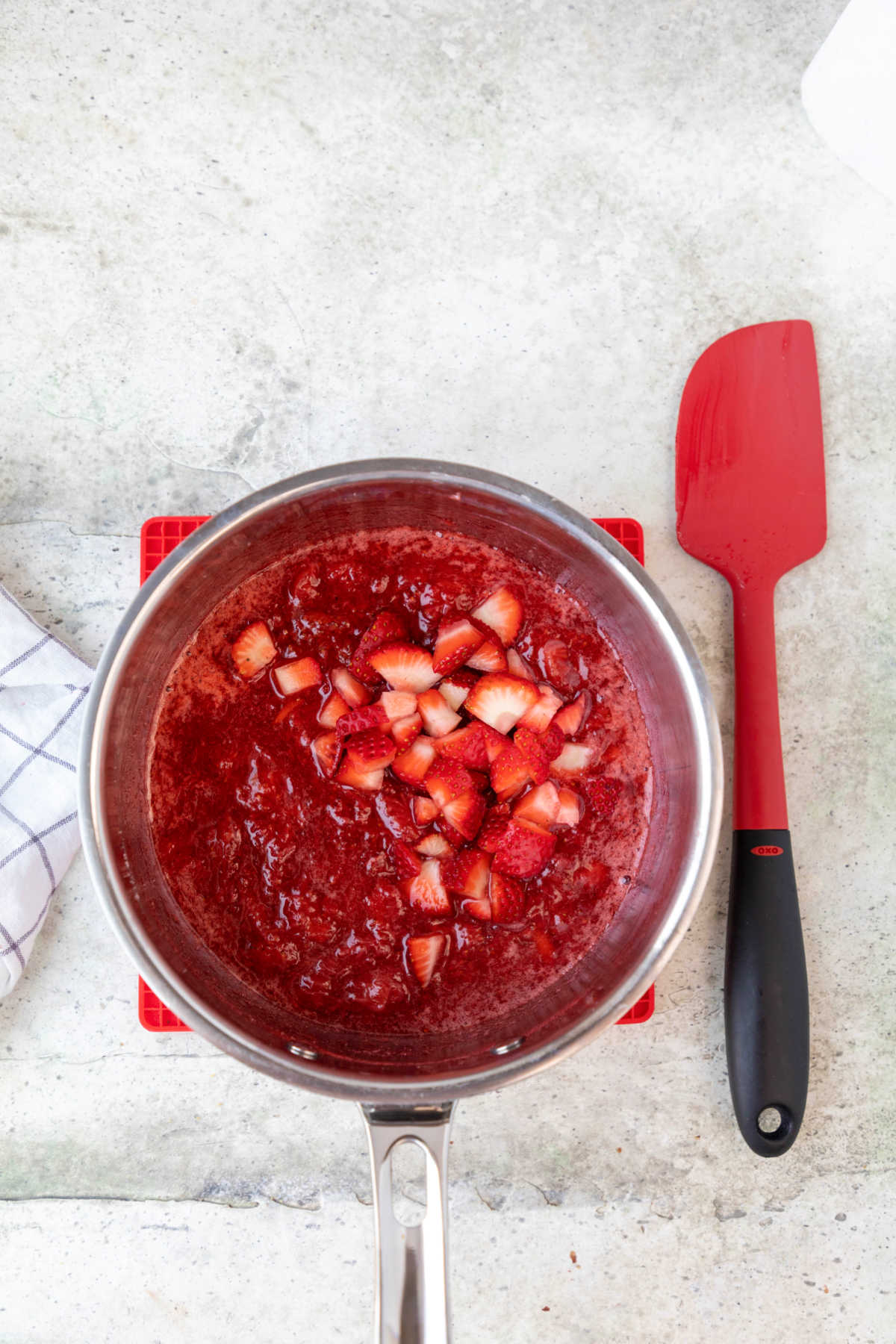 Strawberry sauce with fresh strawberries sitting on top. 