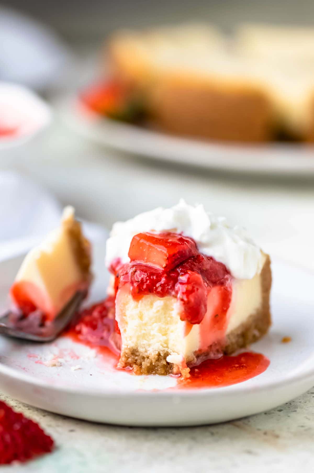 Strawberry topping on cheesecake with a bite out of the cheesecake.