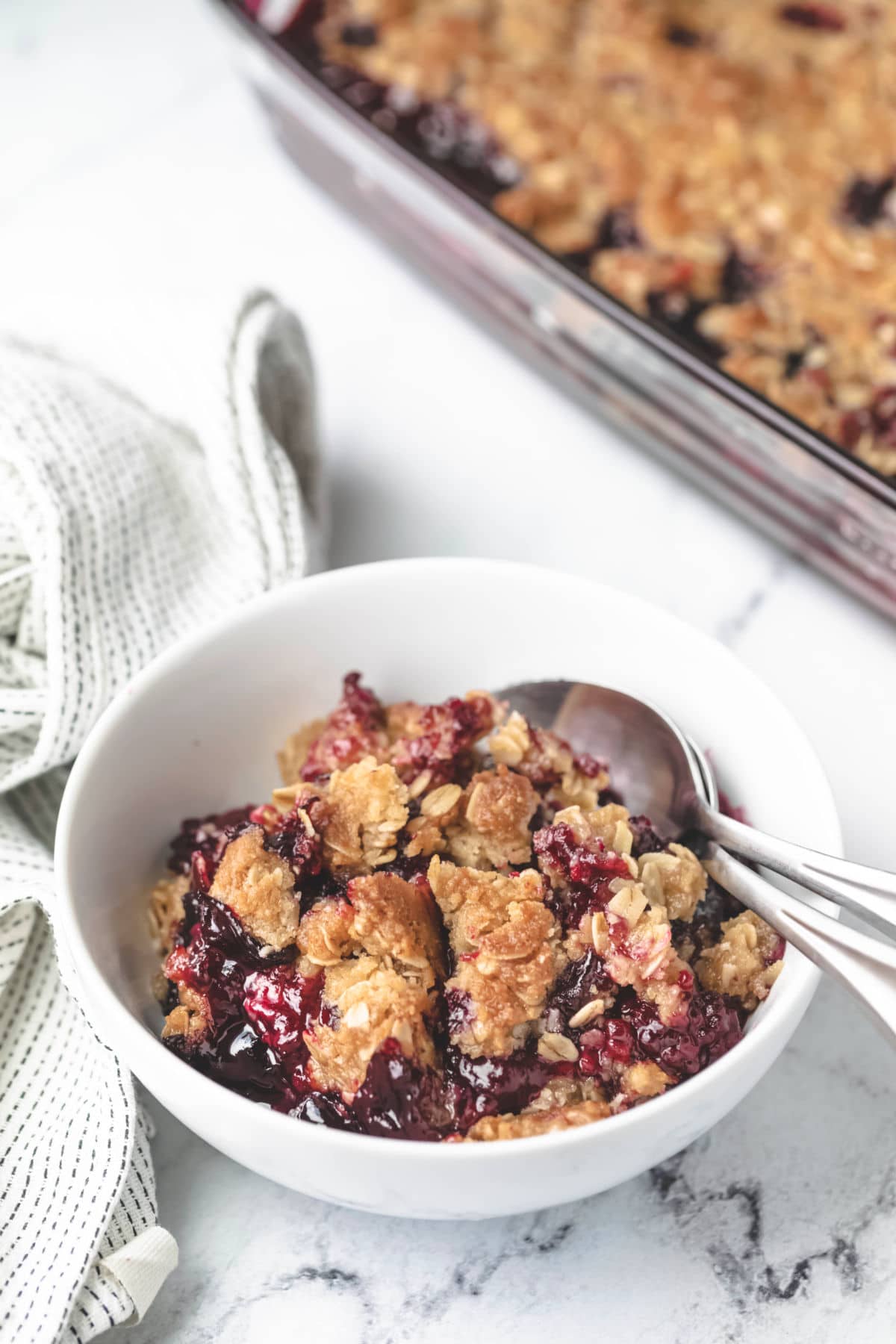 Bowl of triple berry crisp next to a dish of crisp. 