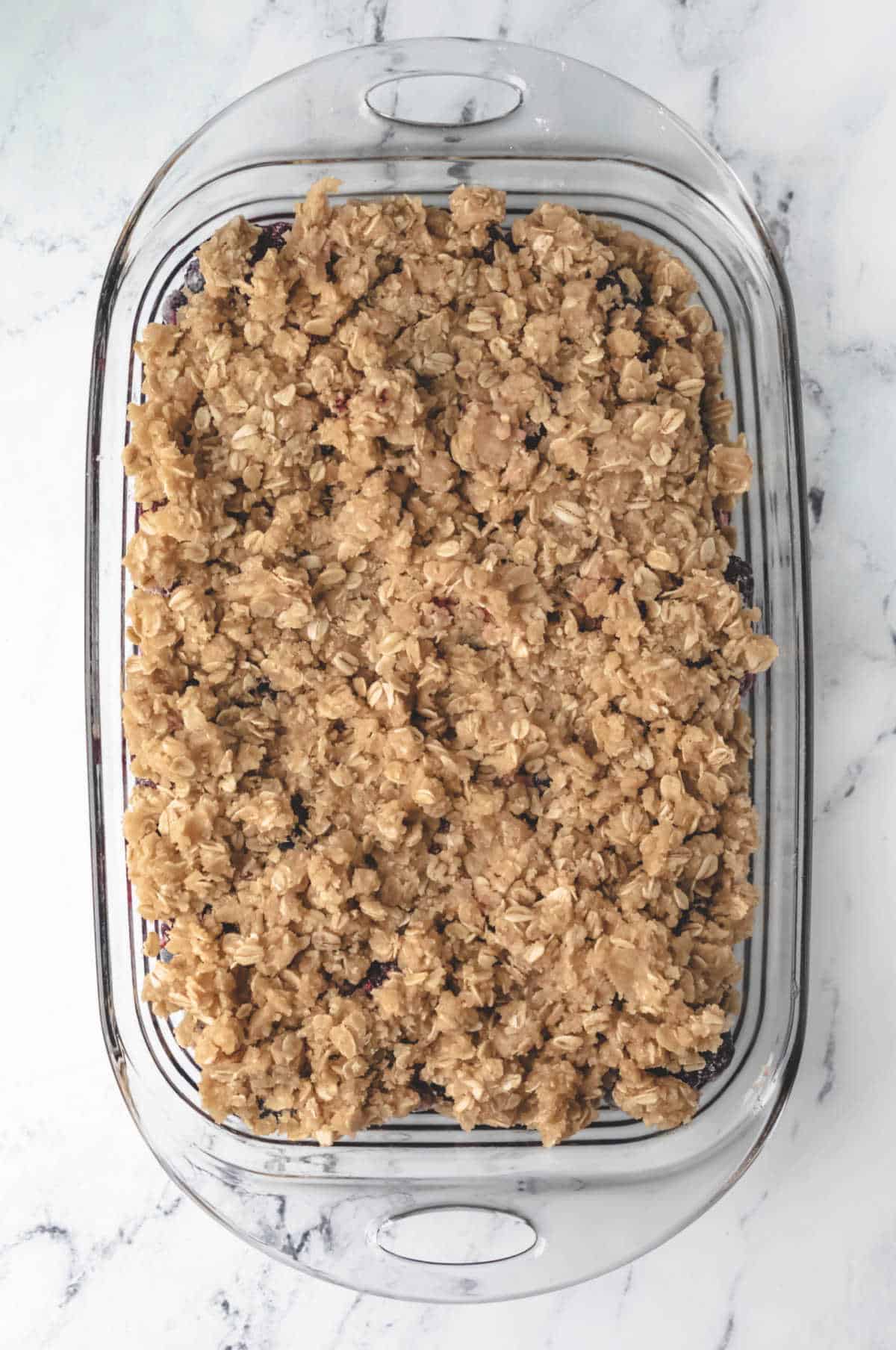 Unbaked berry crisp in a glass baking pan. 