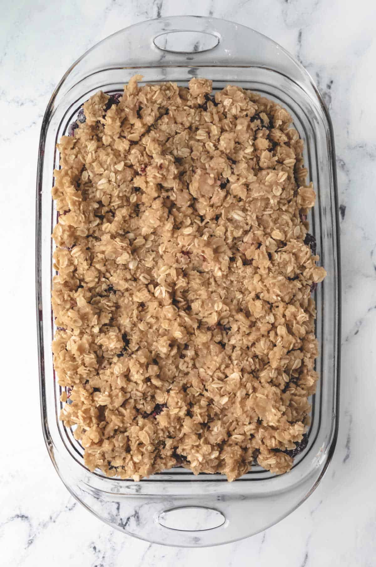 Unbaked berry crisp in a glass baking pan.