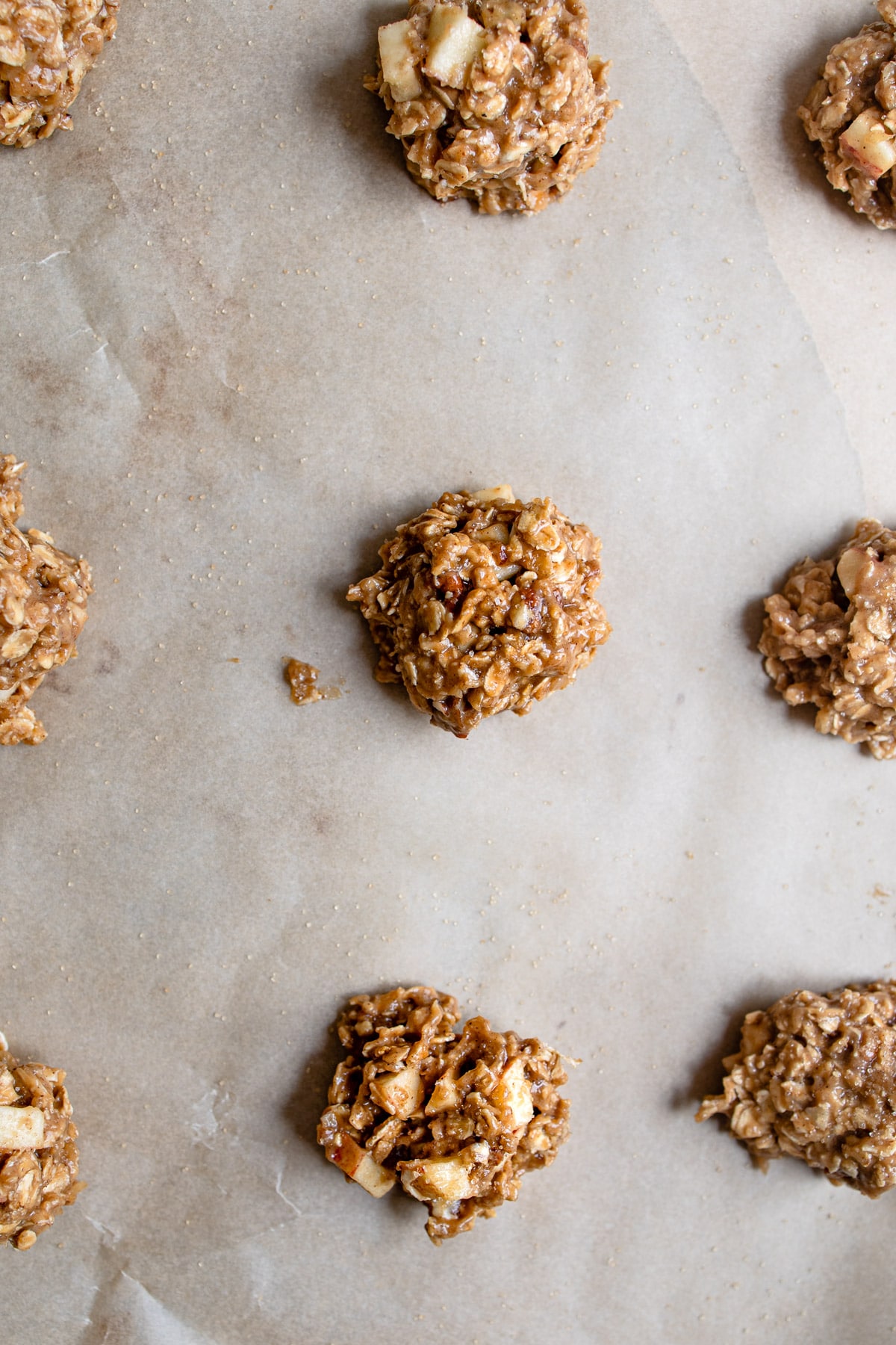 Unbaked apple crisp cookies on parchment paper.