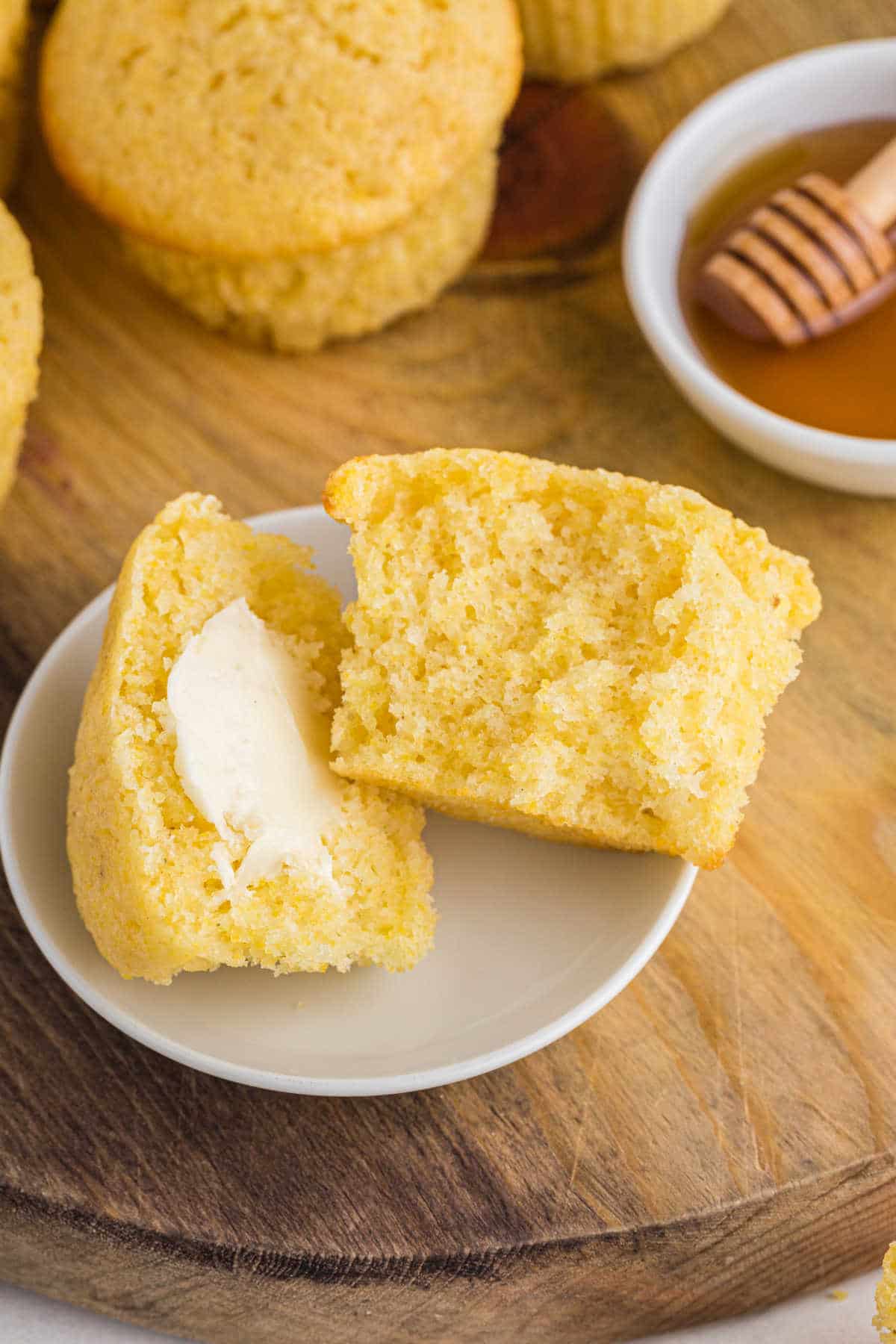 Cornbread muffin cut in half on a white plate. 