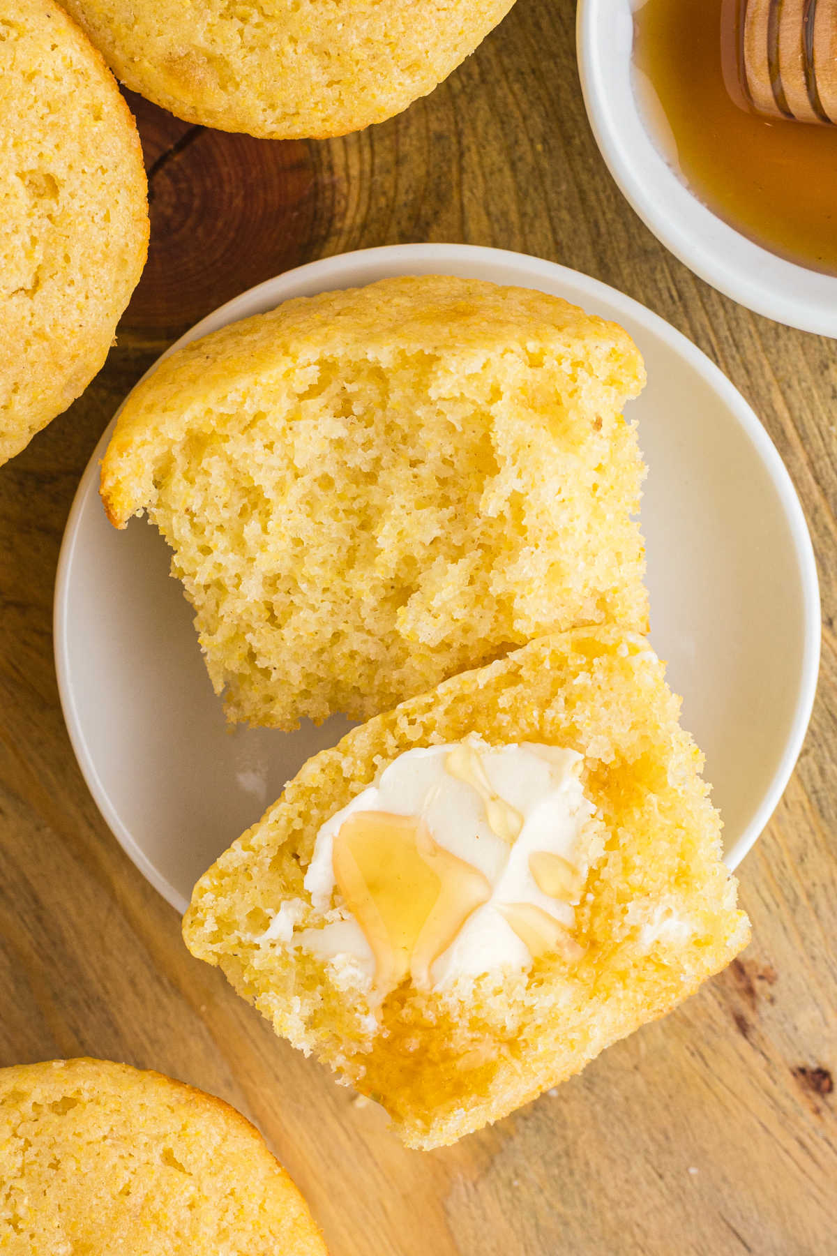 Close up photo of cornbread muffin with butter and honey on it.