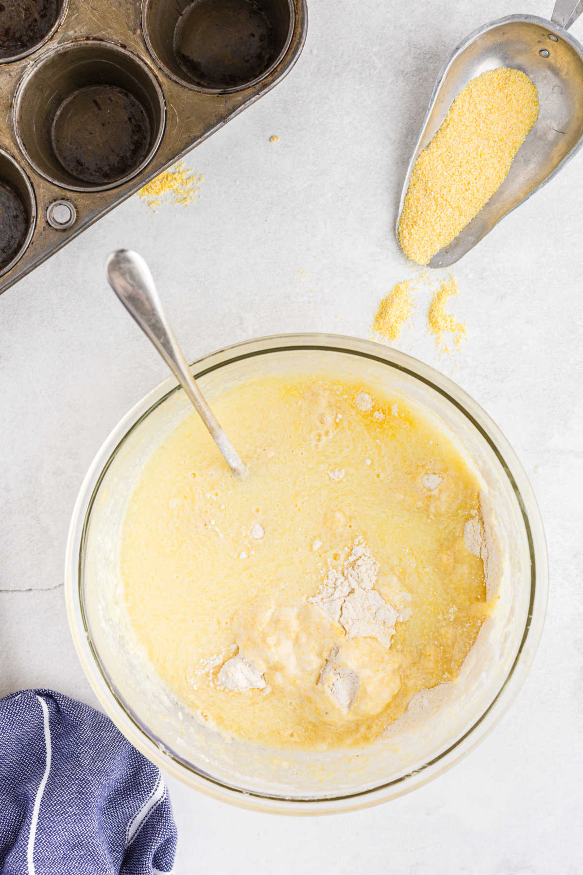 Dry ingredients mixing into wet ingredients for cornbread muffins.