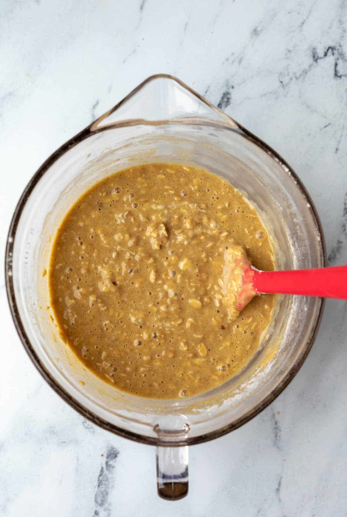 Apple cinnamon oatmeal muffin batter in a glass mixing bowl. 