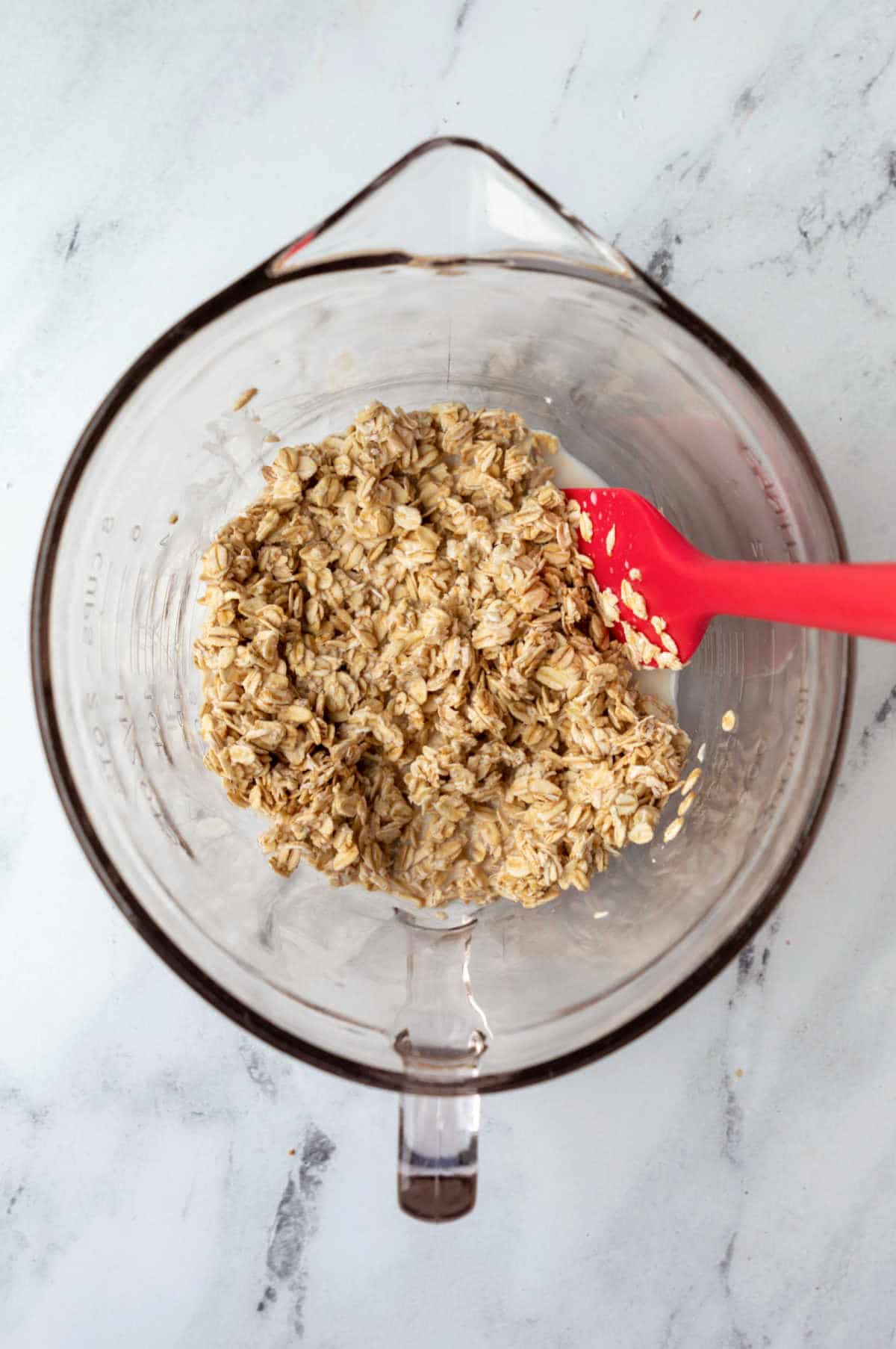 Oats and milk in a glass mixing bowl. 