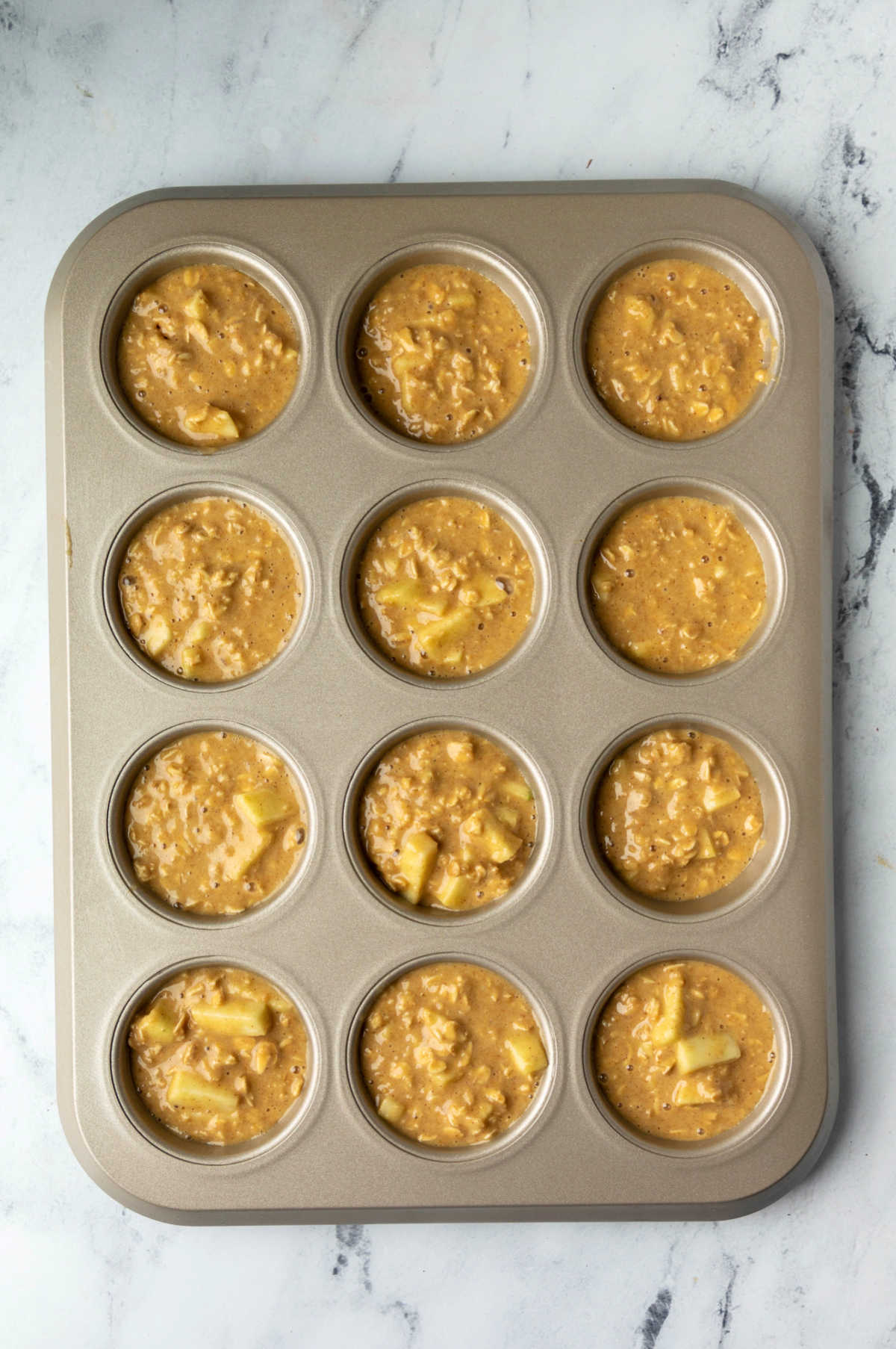 Apple cinnamon oatmeal muffin batter in a muffin tin.