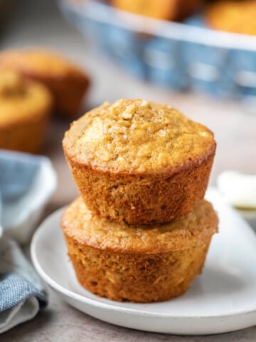 Two apple cinnamon oatmeal muffins stacked on a plate.