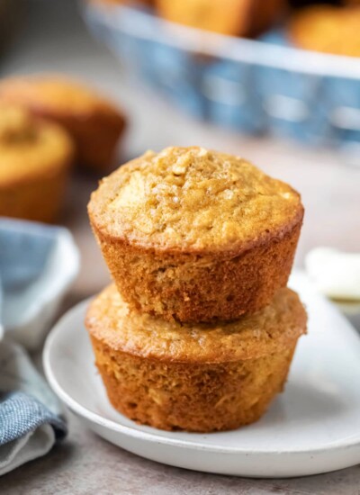 Two apple cinnamon oatmeal muffins stacked on a plate.