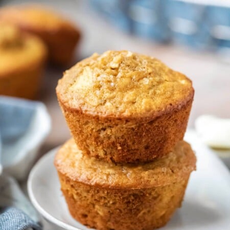 Two apple cinnamon oatmeal muffins stacked on a plate.