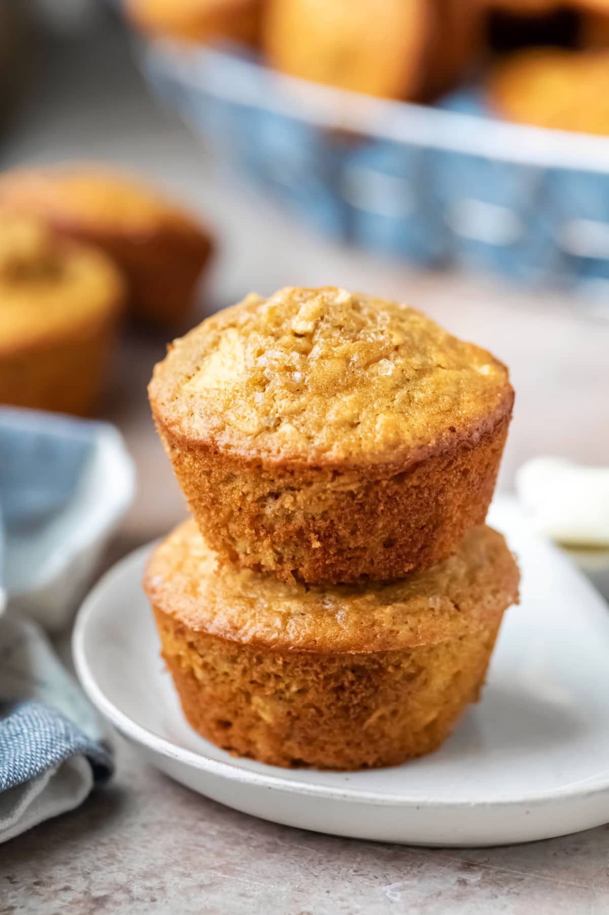 Two apple cinnamon oatmeal muffins stacked on a plate. 