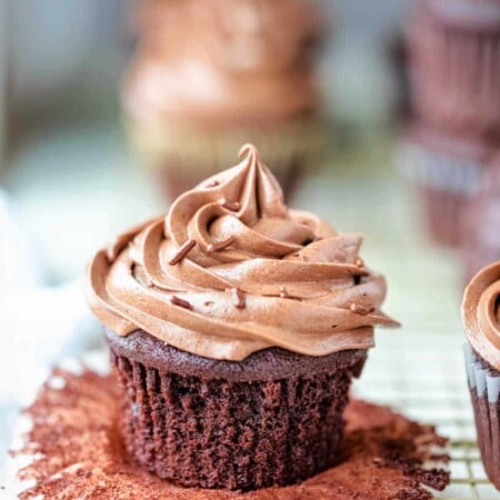 Chocolate cream cheese frosting on a chocolate cupcake with the wrapper pulled down.