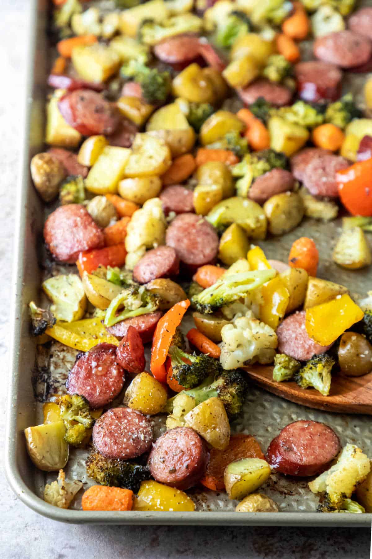 Wooden spoon and roast veggies on a sheet pan.