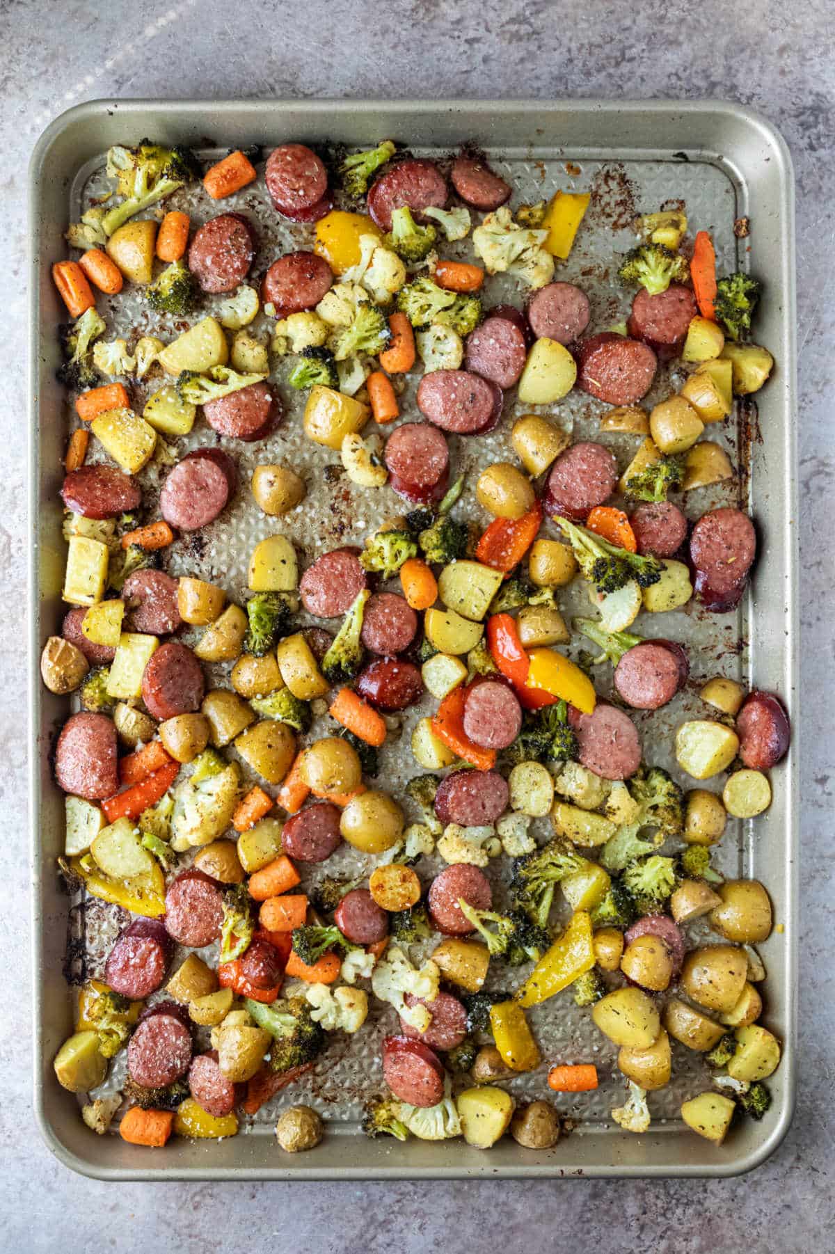 Baked sausage and vegetables on a sheet pan. 