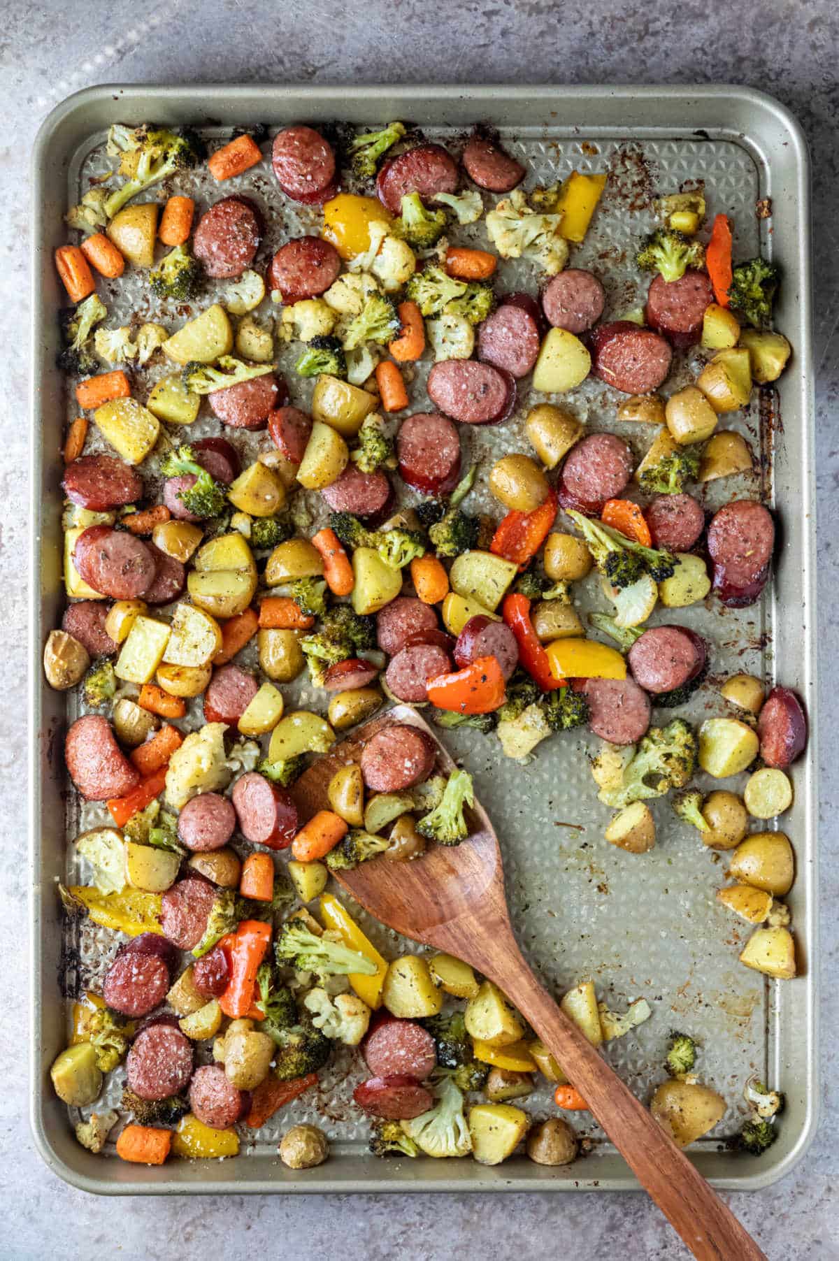 Wooden spoon scooping up roast vegetables.